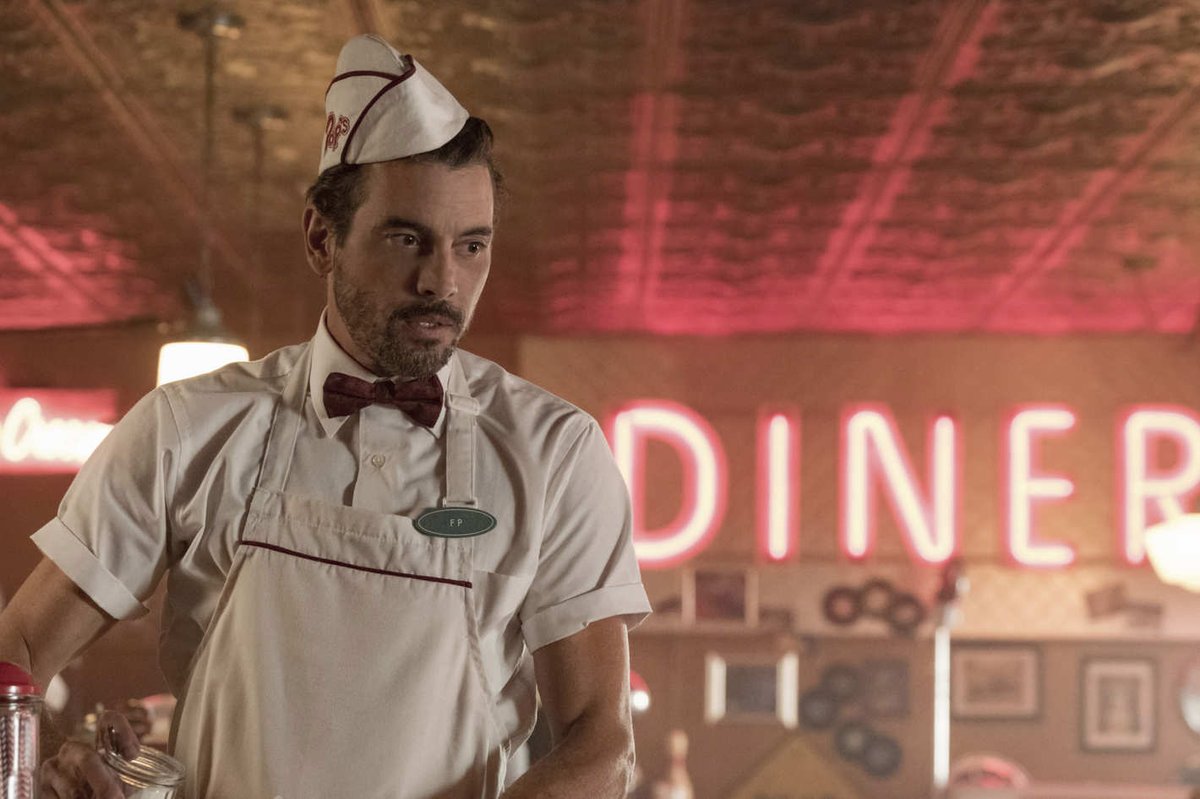 A screencap from the tv series Riverdale. 90s bad boy Skeet Ulrich dressed in a Pop's Diner uniform with bowtie and hat.