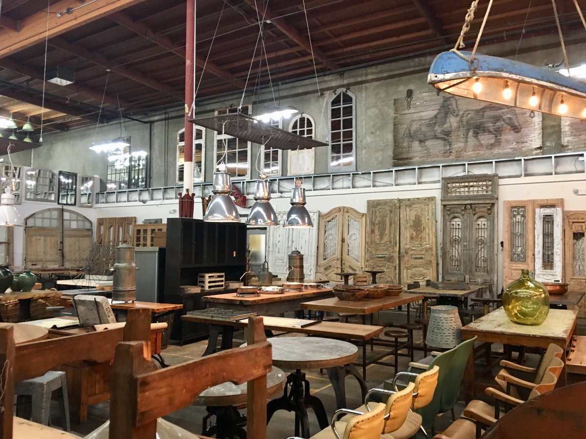 A warehouse filled with antique doors, tables, and theater chairs.