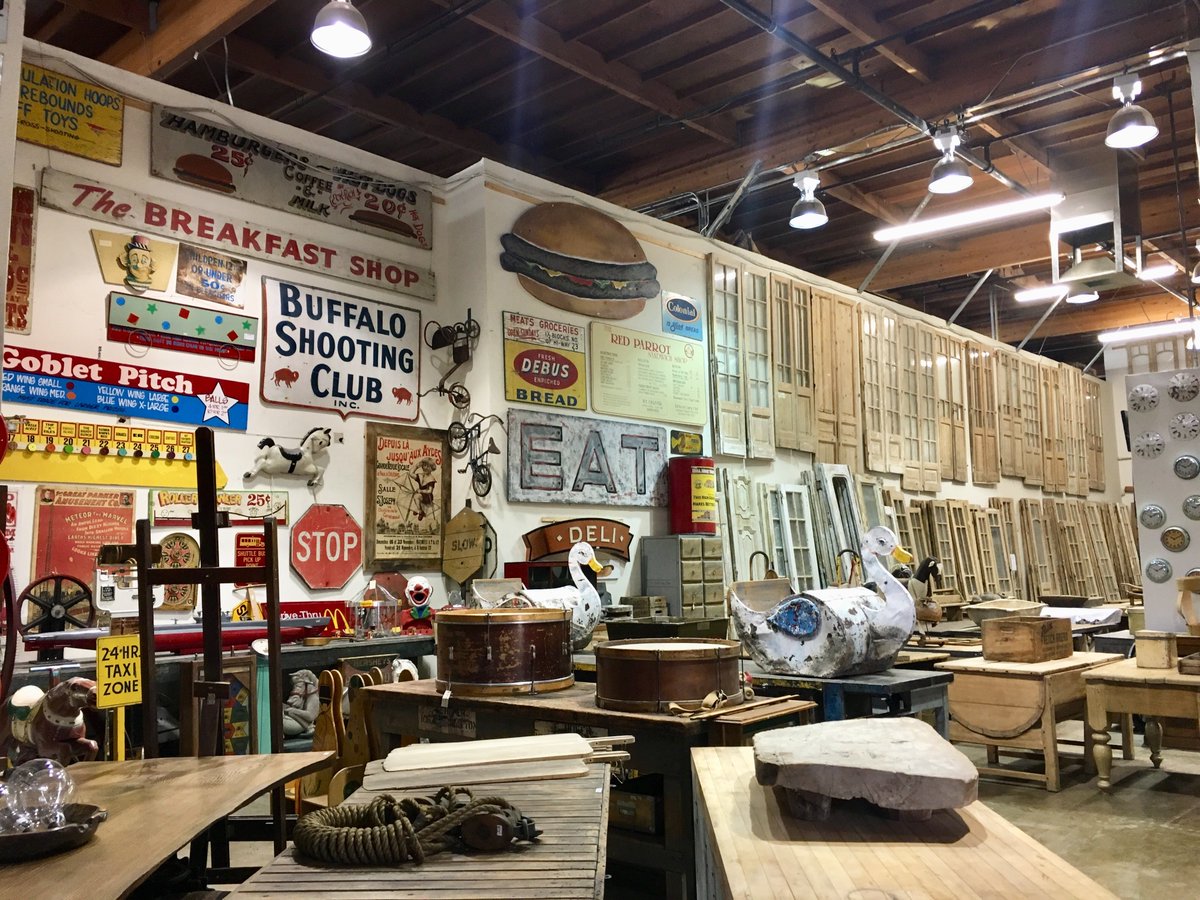 An antique warehouse with vintage signage, carnival games, and garden doors.