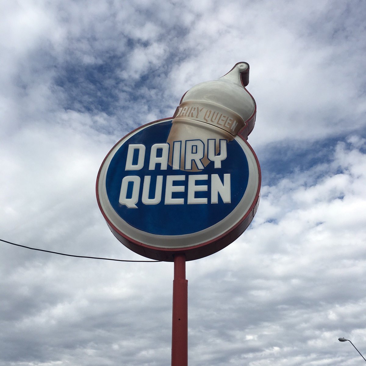 A vintage Dairy Queen sign with a painted ice cream cone