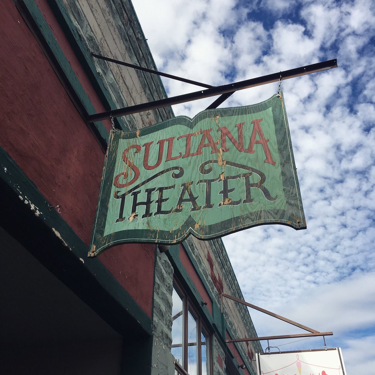 An old sign shaped like a book that reads “Sultana Theater”