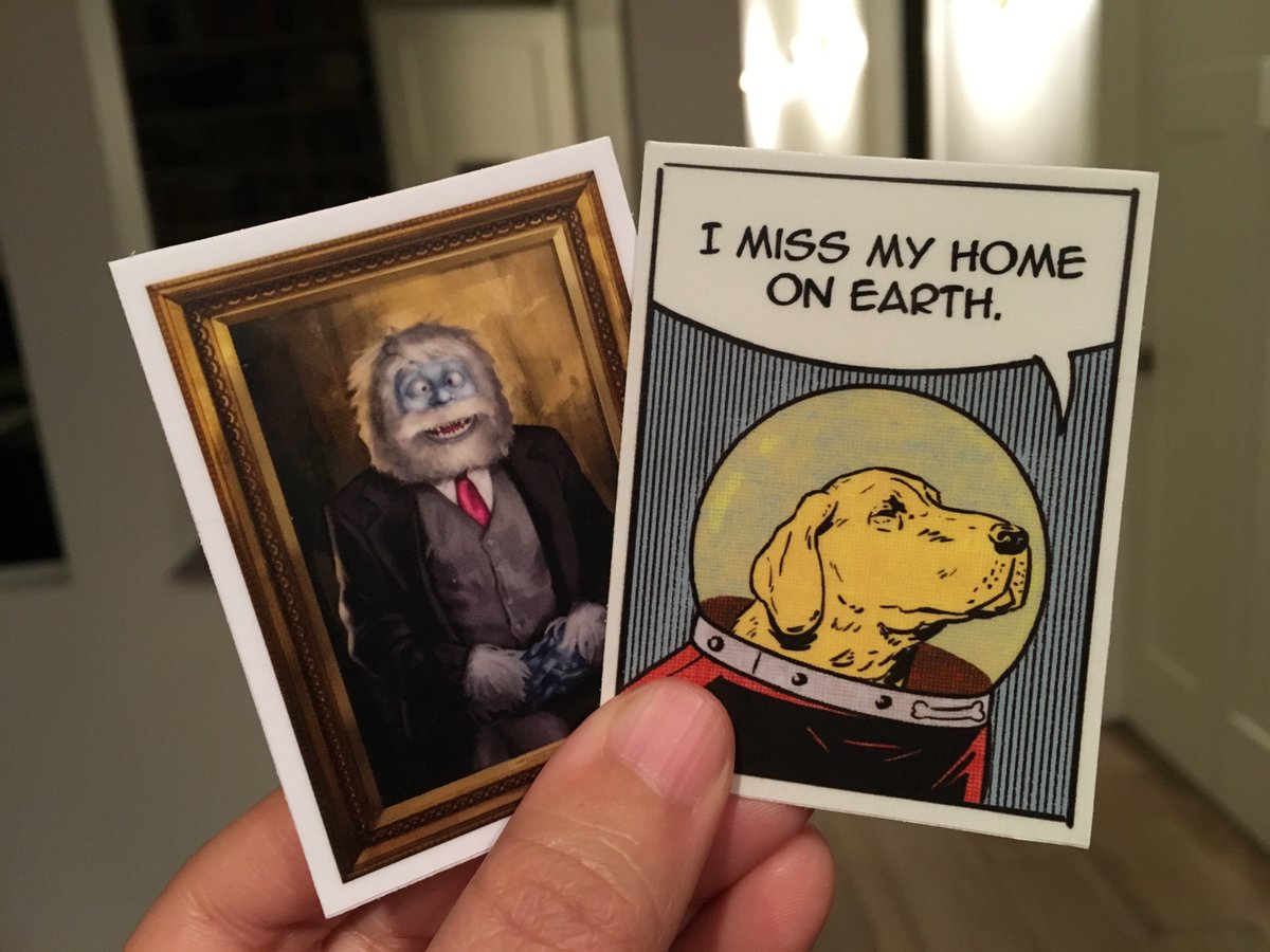 Two rectangular stickers: a portrait of a yeti in a three-piece suit and a dog in an spacesuit saying “I miss my home on Earth.”