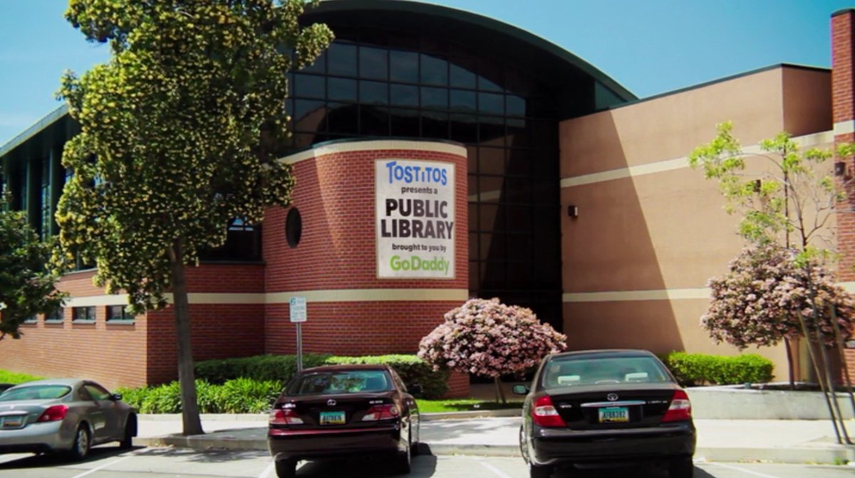 A building with a large banner that says, “Tostitos presents a public library brought to you by GoDaddy.”