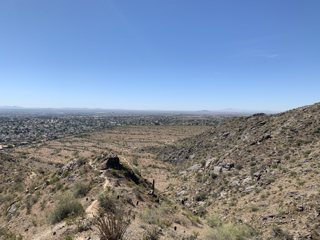 A view of south Phoenix suburbs and blue, clear skies from the desert hills of South Mountain.