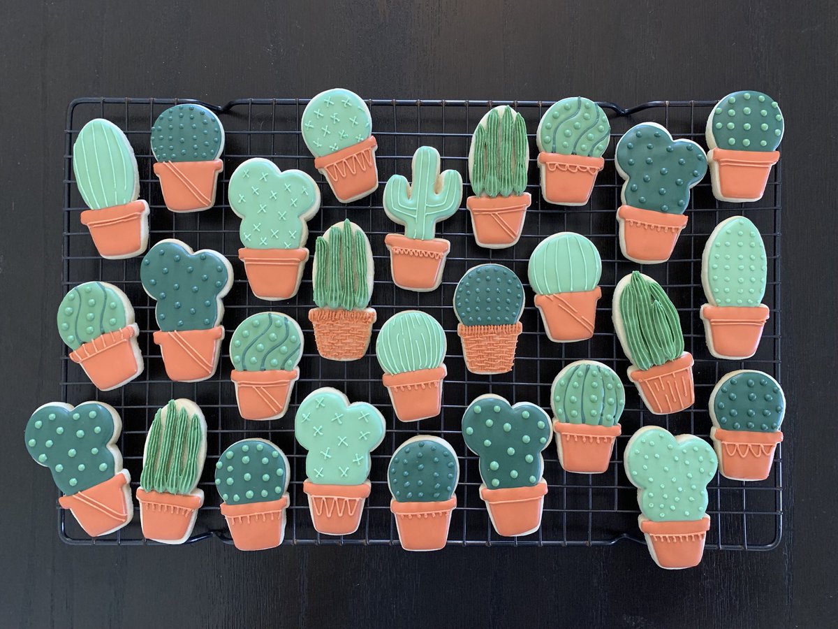 Decorated sugar cookies shaped like cacti in clay pots.