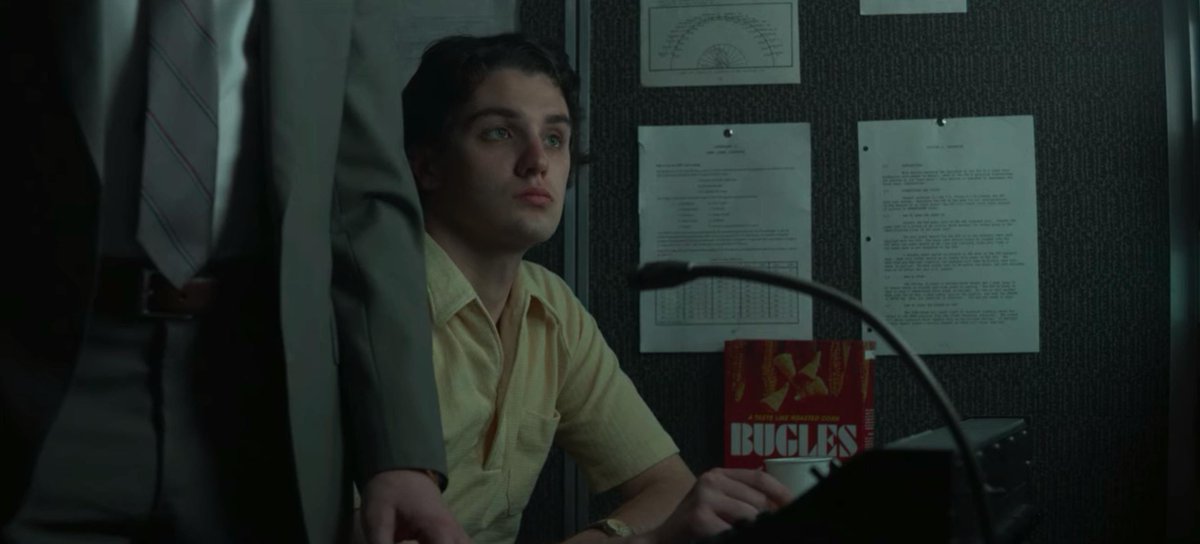 Screenshot from Mindhunter: a man sits in a surveillance van next to a very obvious box of Bugles snacks.