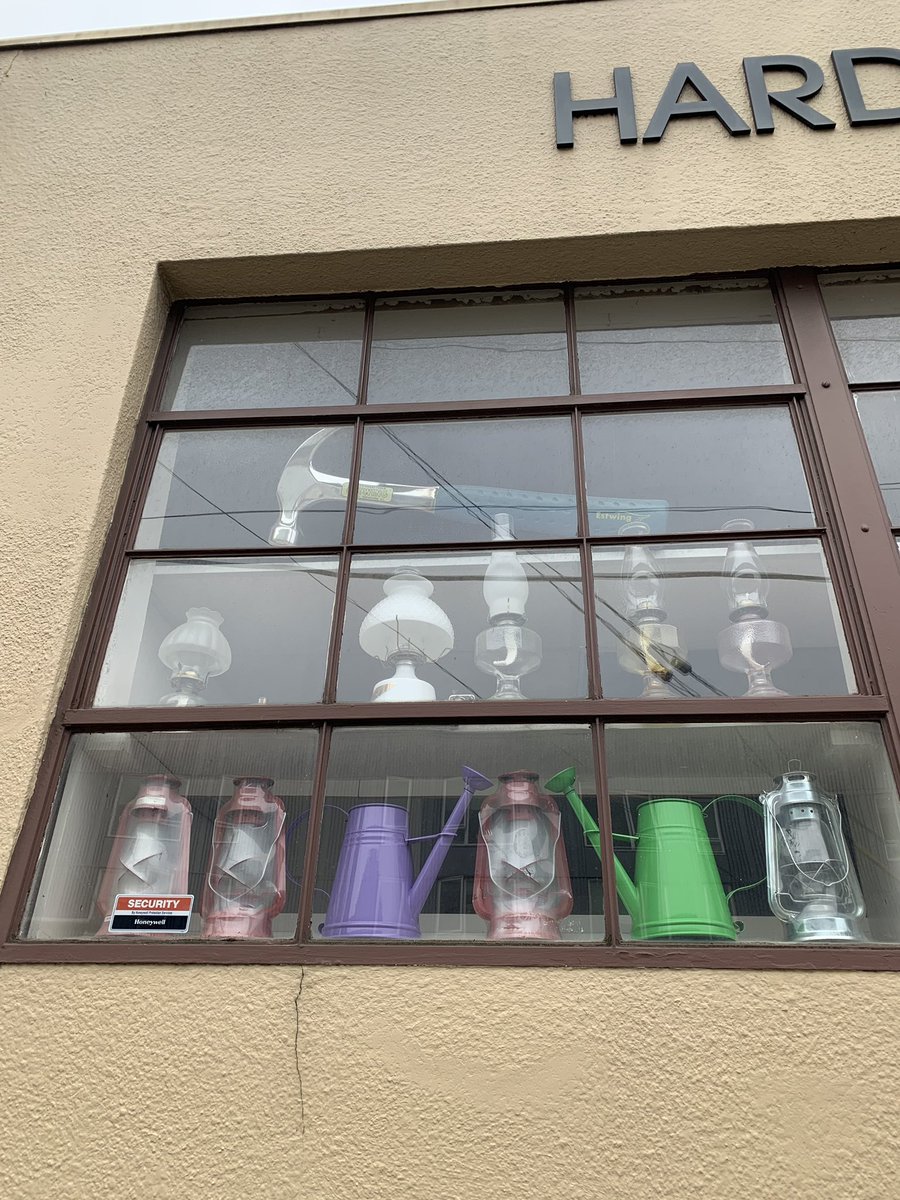 A hardware store’s window display with a giant hammer and oil lanterns for scale.