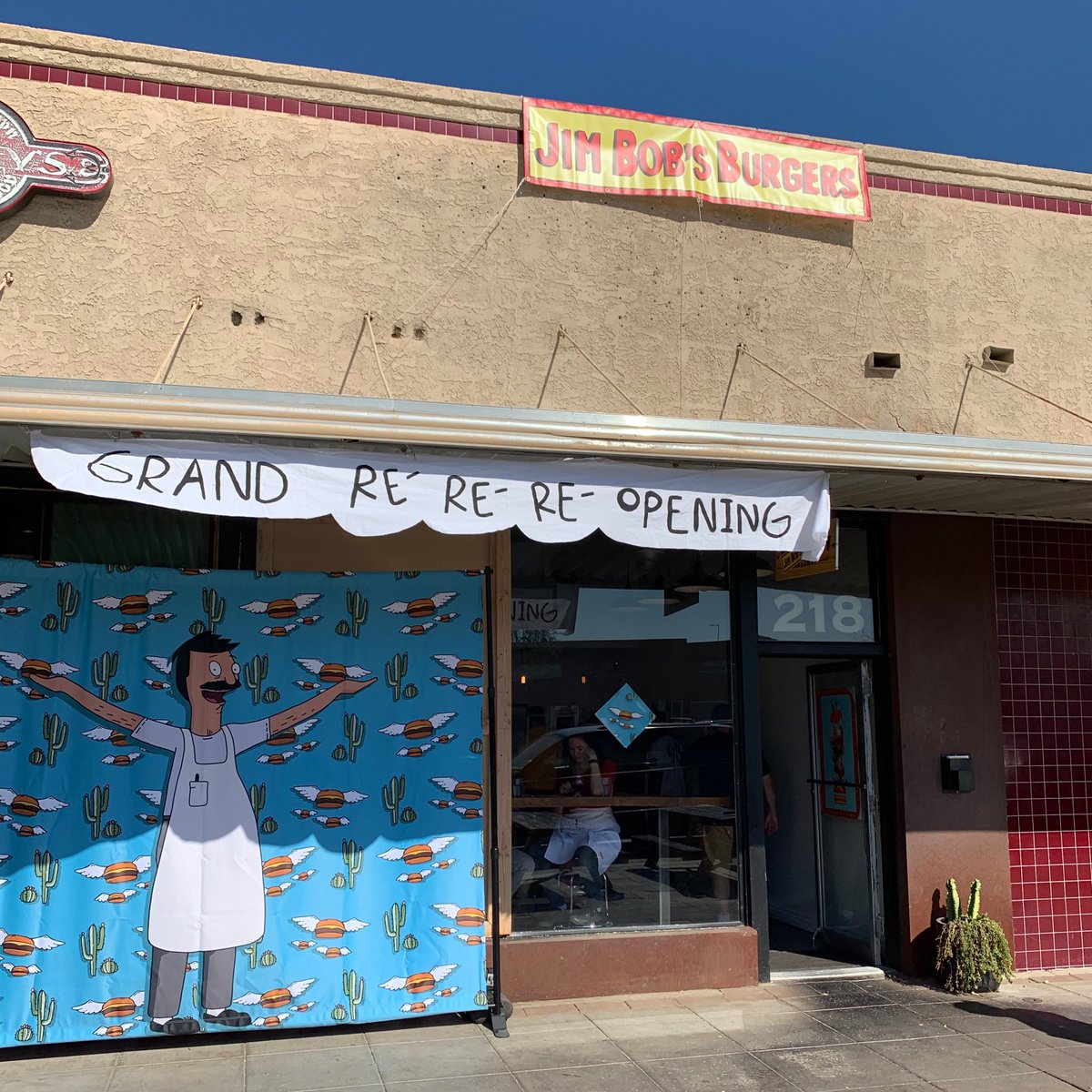 Storefront for Jim Bob's Burgers with a banner saying Grand Re-Re-Re-Opening!