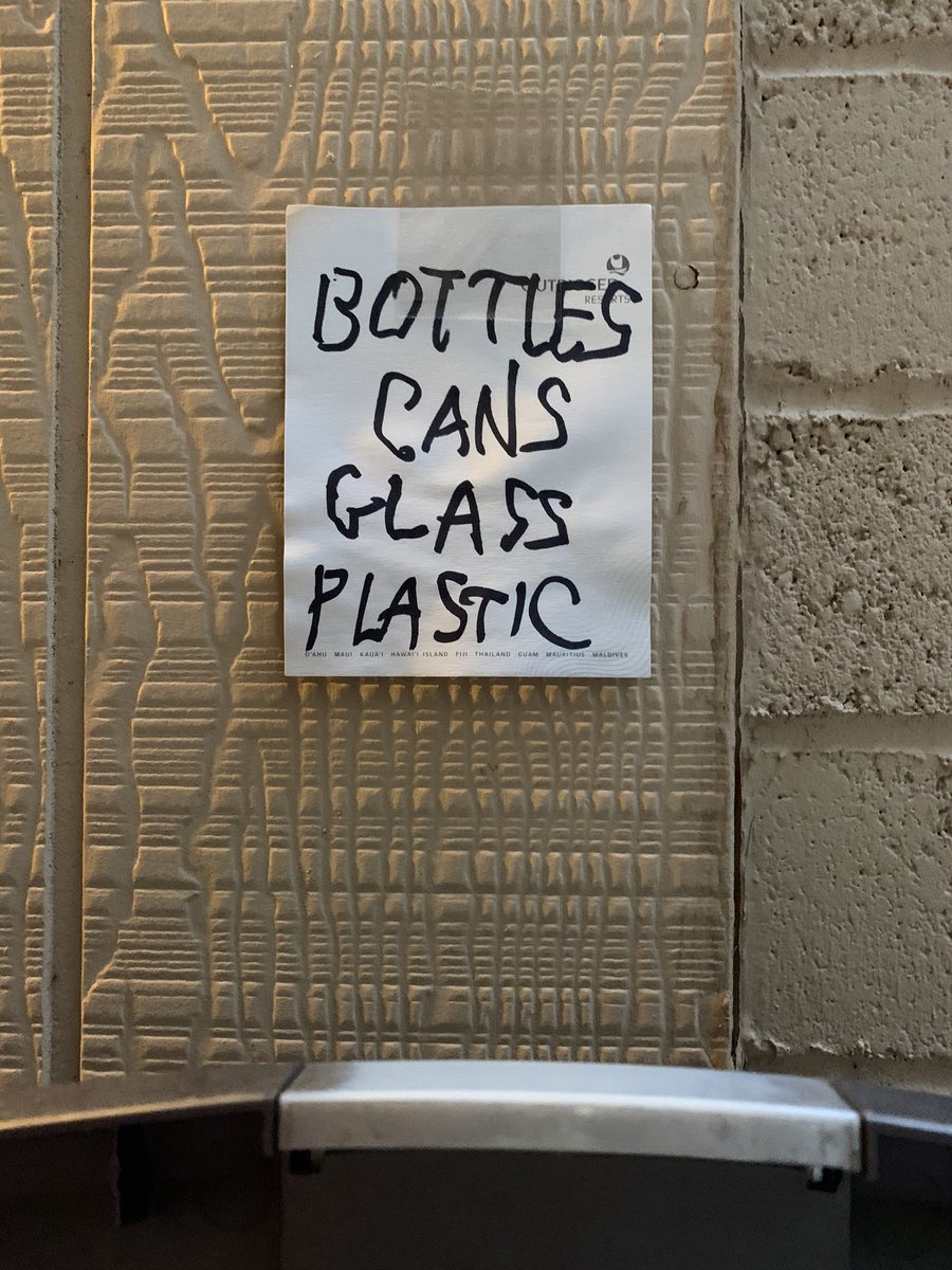 A handwritten note taped to a wall that says “bottles, cans, glass, plastic.”