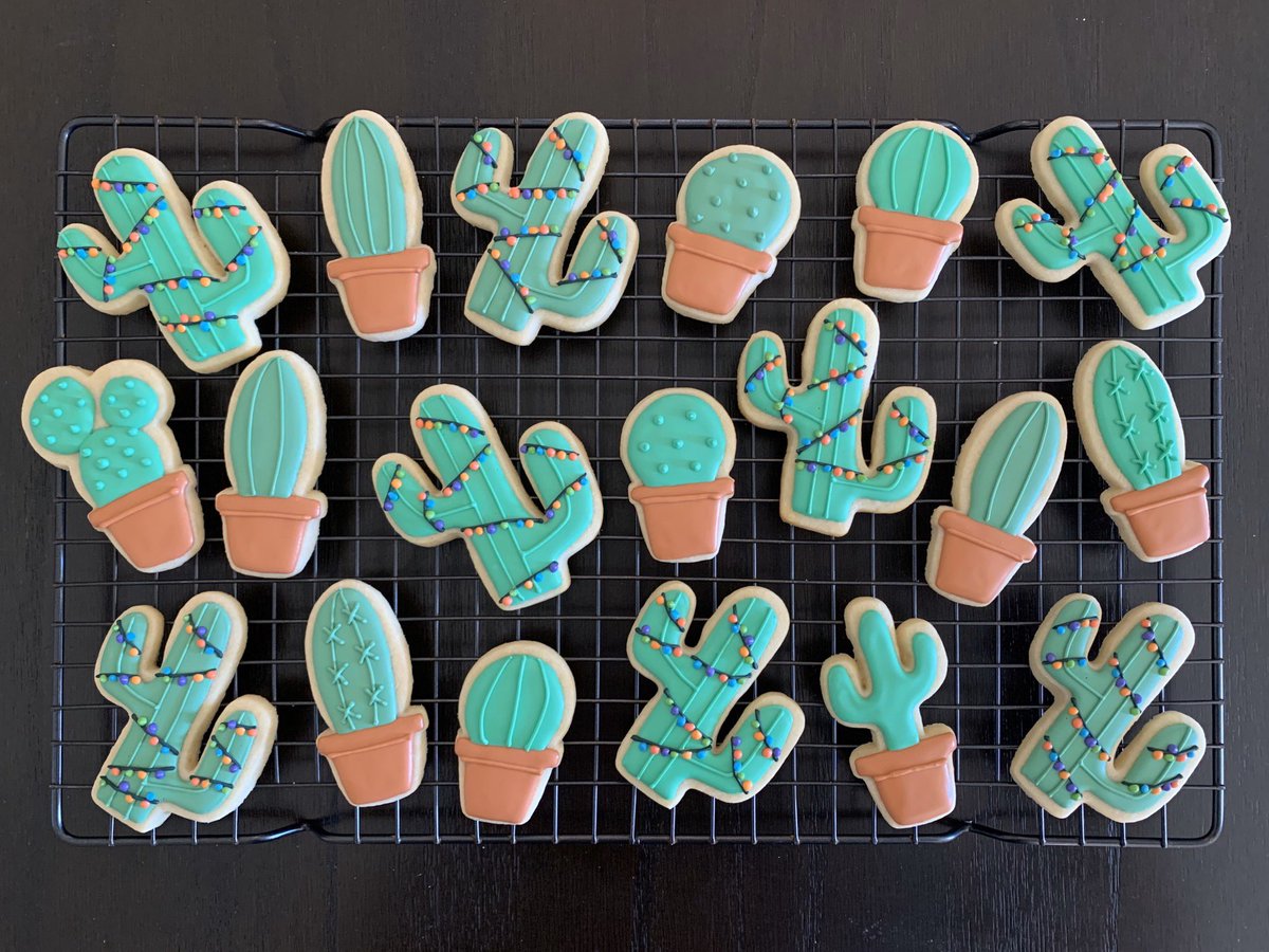 Cookies decorated like cacti, some with holiday lights.