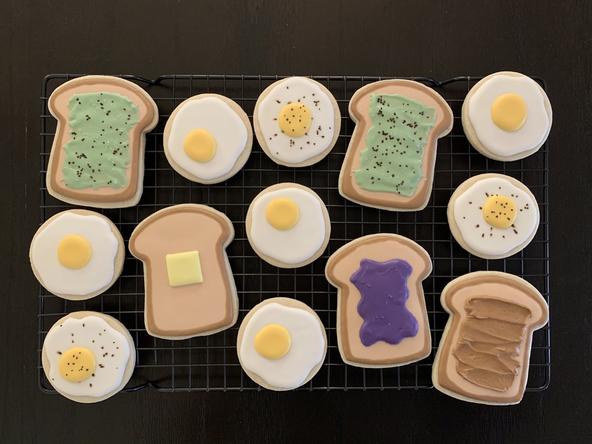 Iced sugar cookies decorated as pieces of toast with jelly, peanut butter, and avocado. Also sunny-side-up eggs sprinkled with pepper.