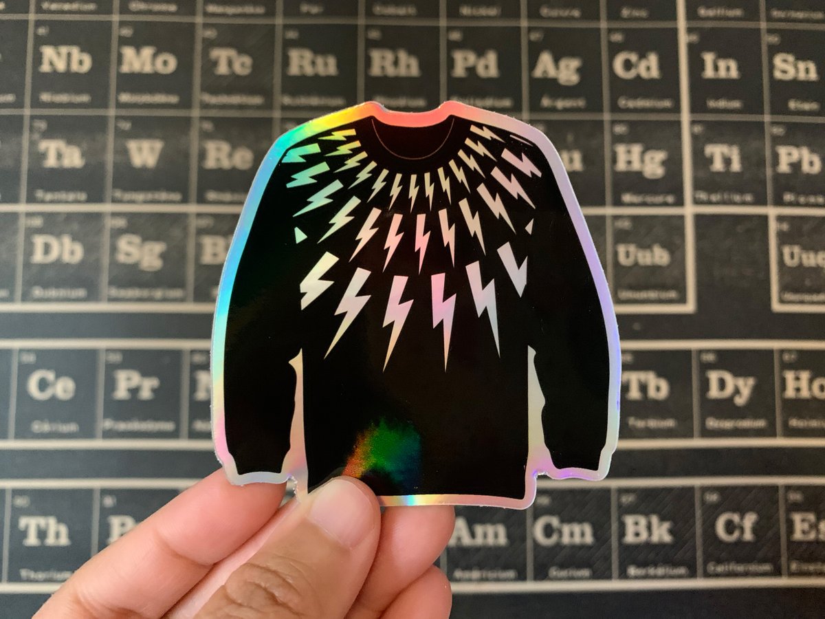 An iridescent hologram sticker of a black sweater with lightning bolts radiating from the collar.