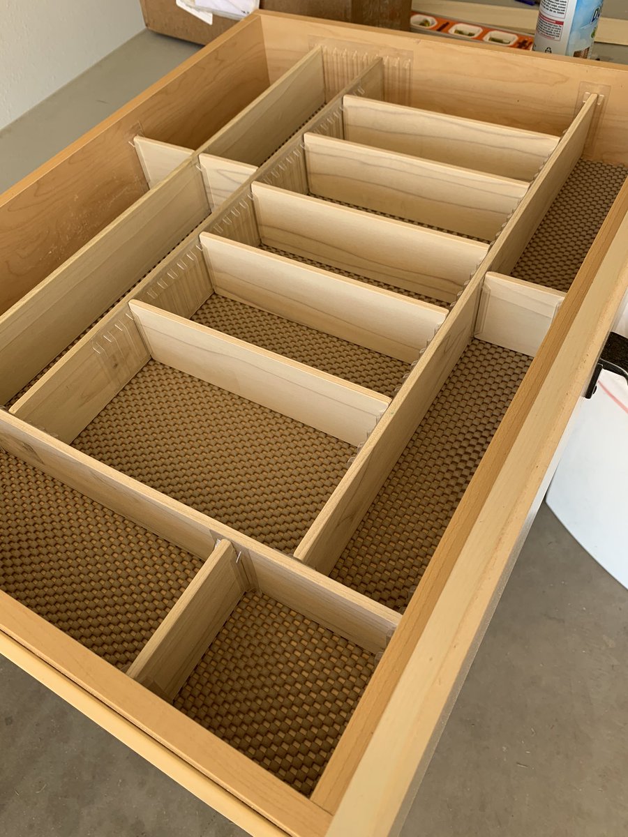 An empty kitchen drawer with cut and connected poplar boards dividing it into sections.