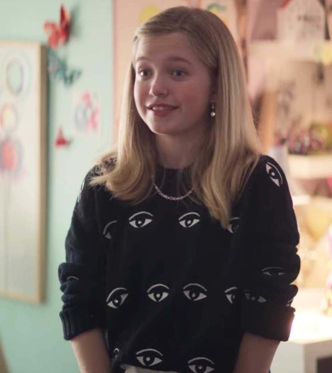 Stacey from the Babysitter’s Club series wearing a black sweater with graphic eyeball pattern.