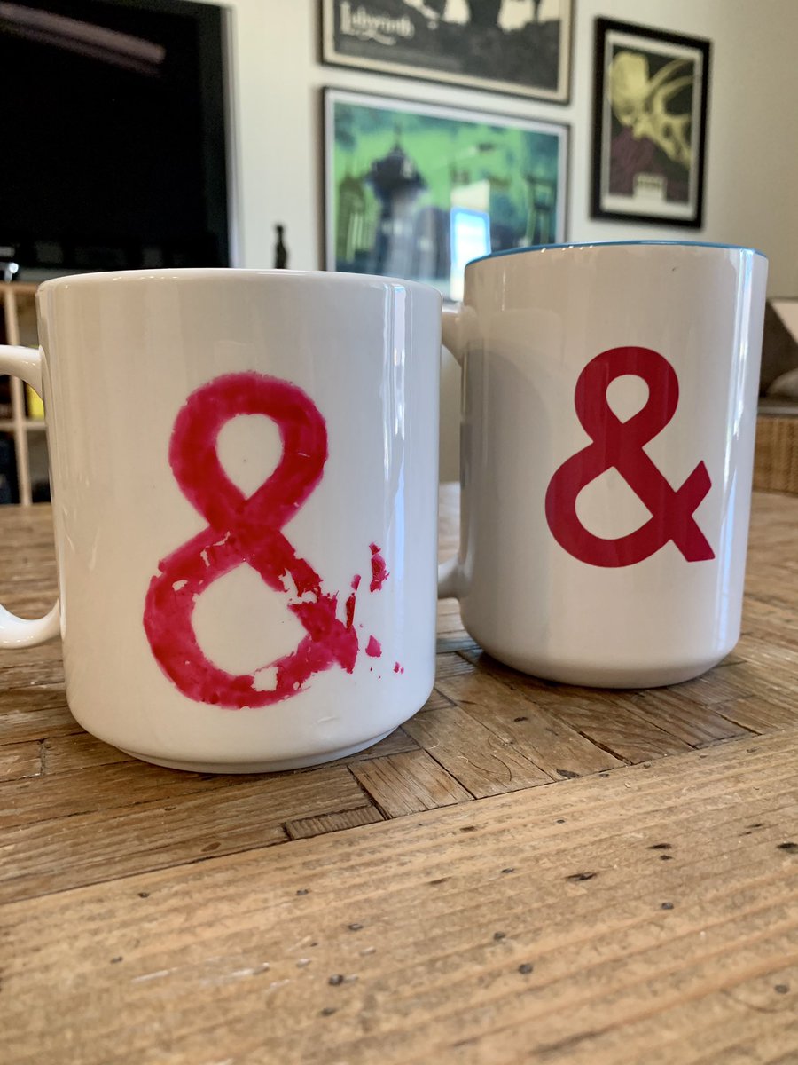 Two mugs each with a pink ampersand, the first has partially rubbed off with years of wear.