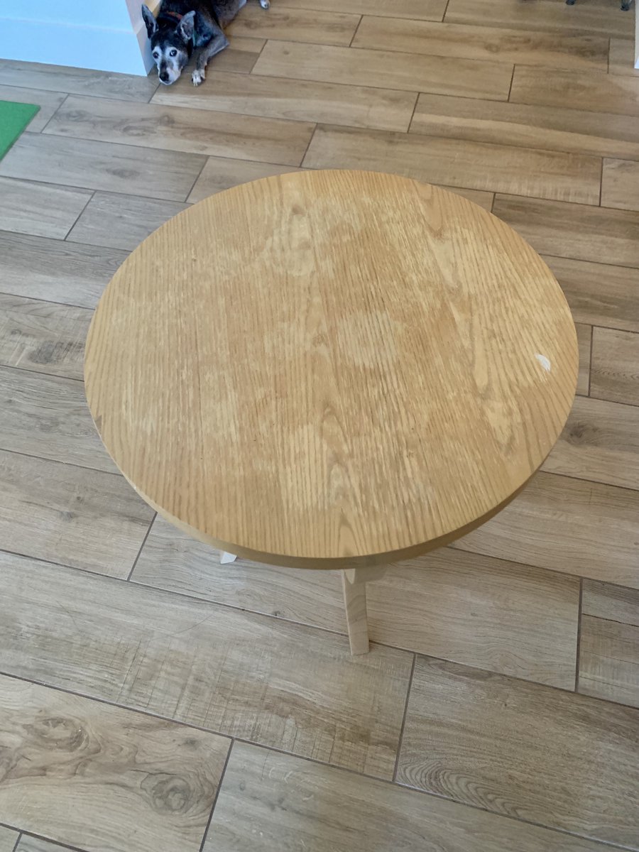 a round wood veneered side table with water and paint stains