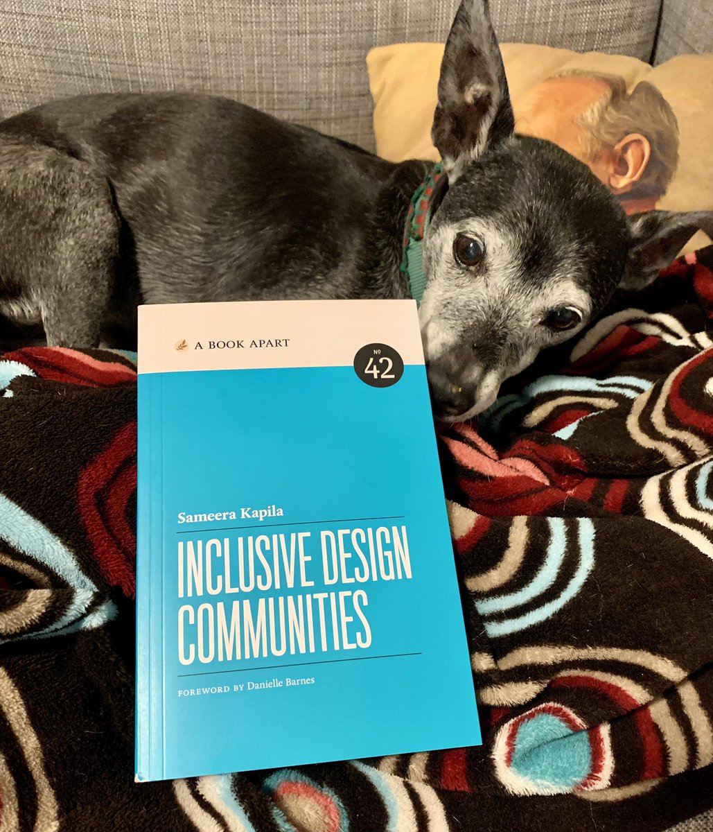 a pup sniffs a copy of Sameera Kapila’s book “Inclusive Design Communities”