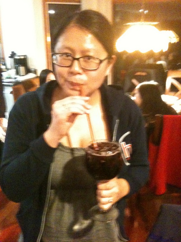 the author sipping a full wine glass of red wine and diet coke