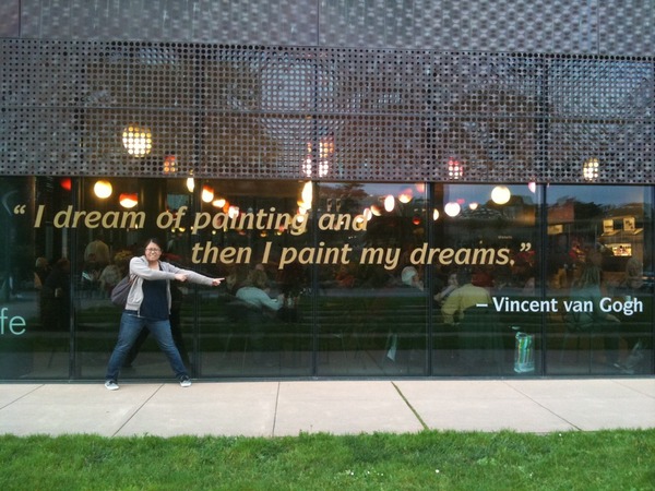 the author pointing at a big quote on the wall: “I dream of painting and then I paint my dreams” —Vincent van Gogh