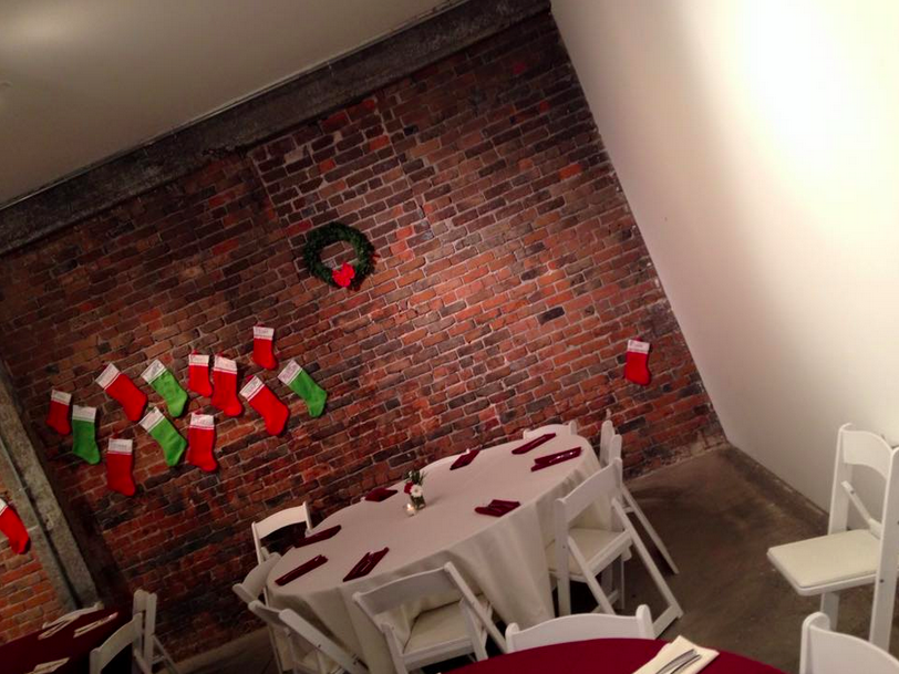 a bunch of stockings on a brick wall and far away in the corner, Lynn’s stocking