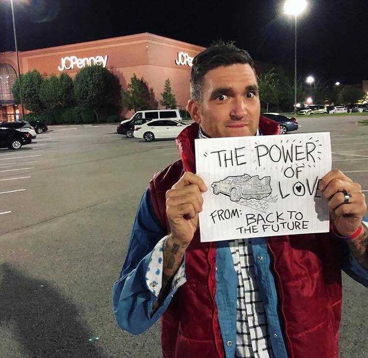 Jordan dressed as Marty McFly holding a paper with “The Power of Love” drawn on it