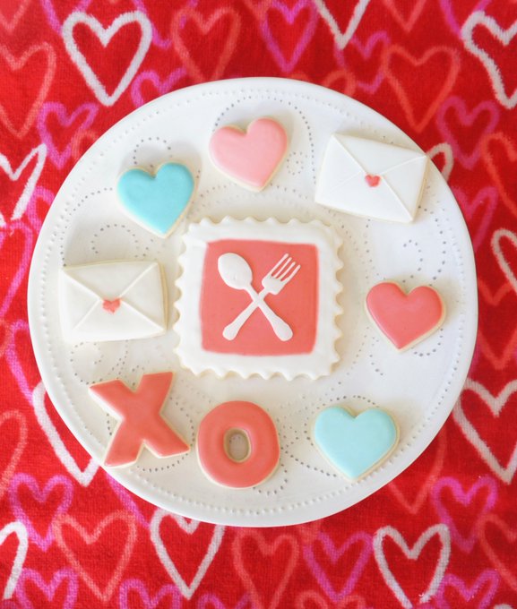 frosted sugar cookies in the shape of hearts, love letters, and Xs andOs