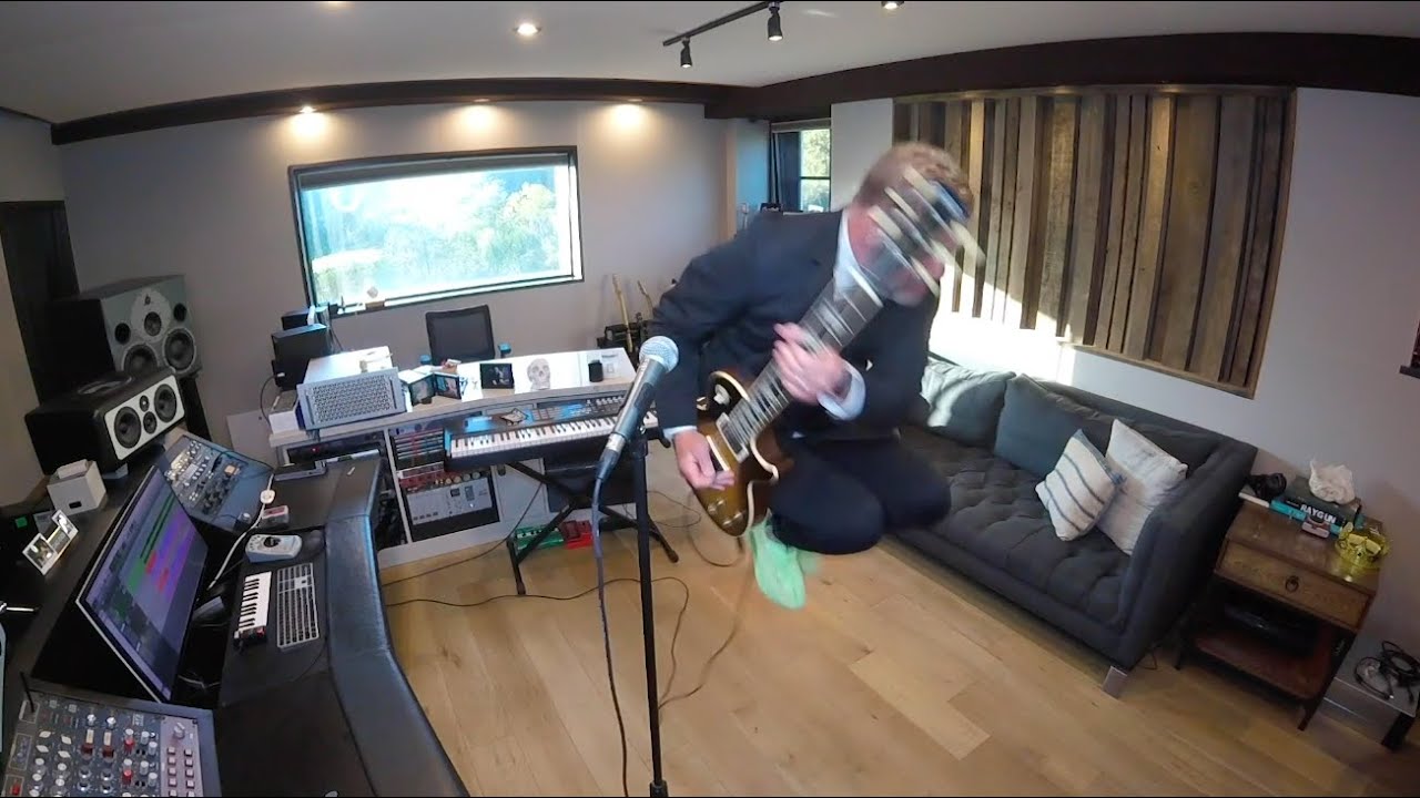 John Feldmann playing guitar and jumping in his home studio