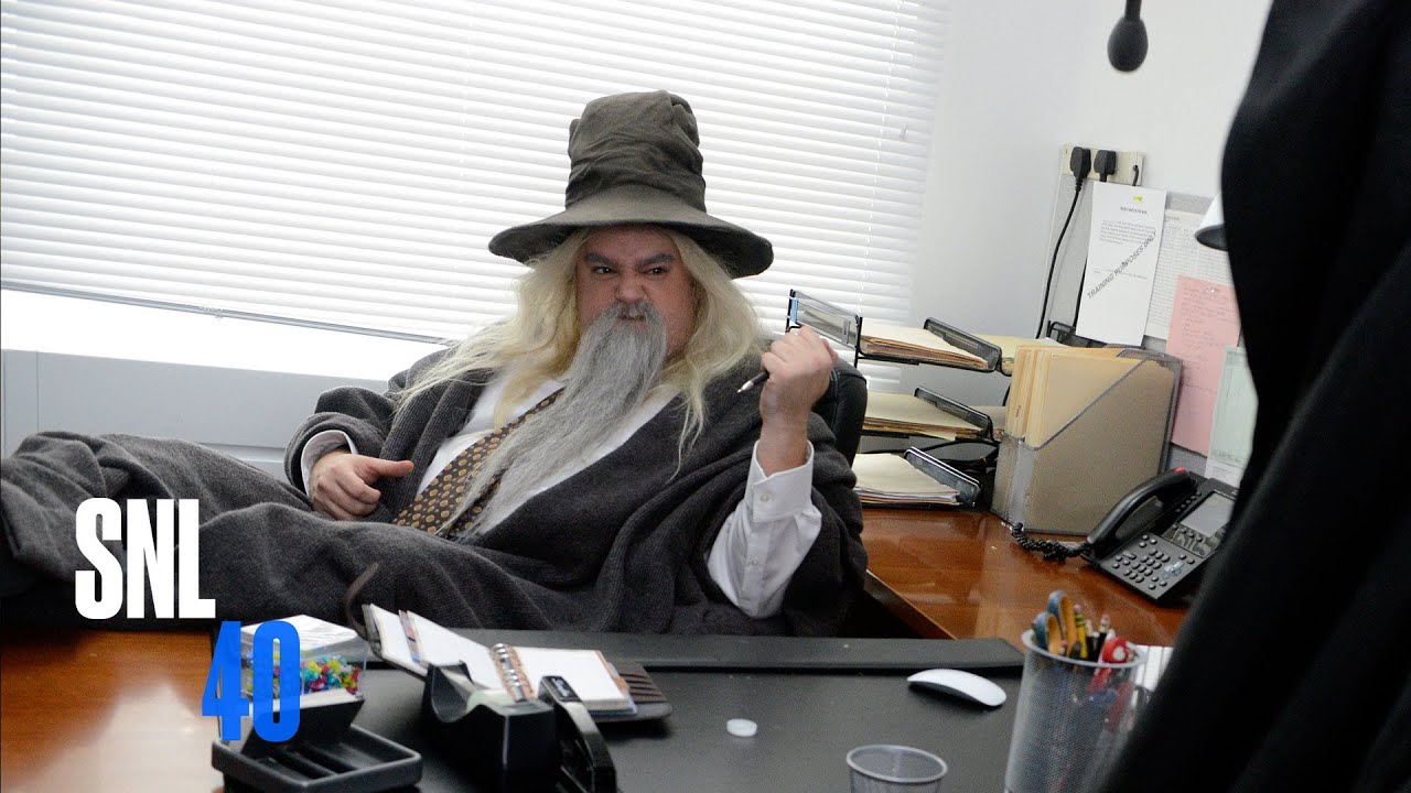 guy dressed as Gandalf working a desk job