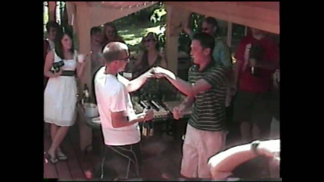 home video of a backyard party and two guys are opening a bottle of champagne