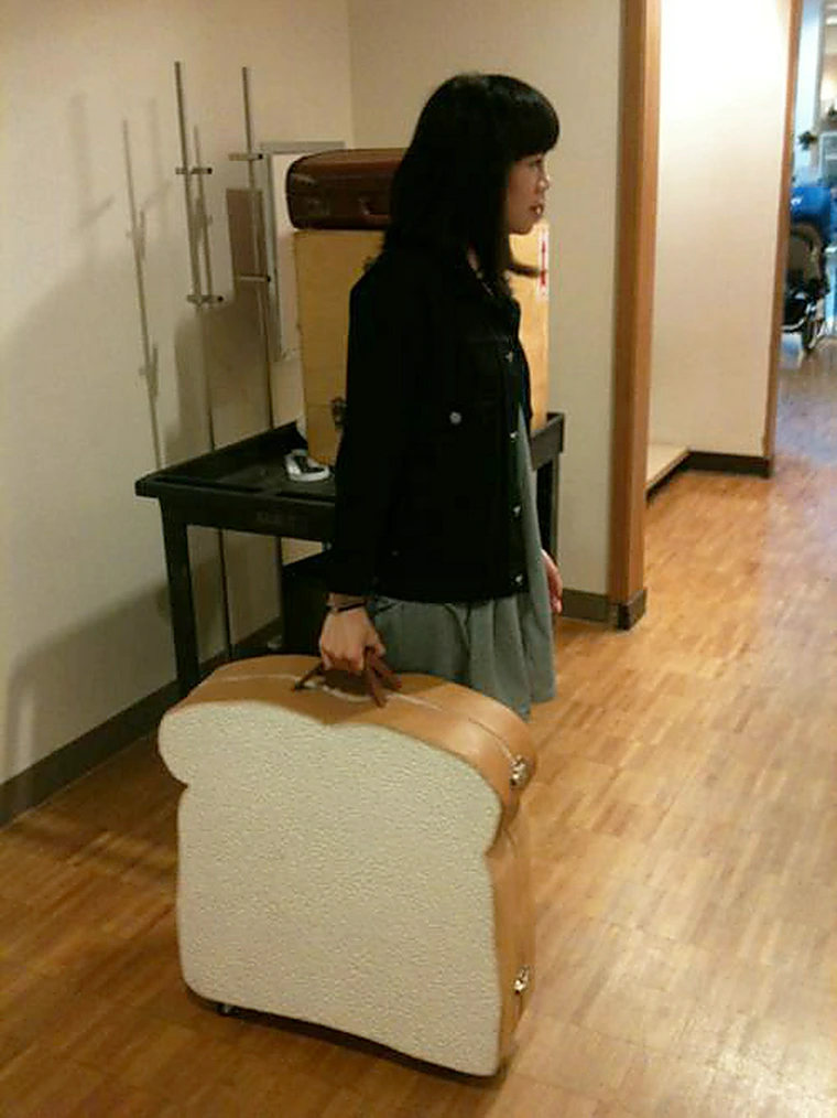 girl holding a suitcase shaped like a big piece of bread